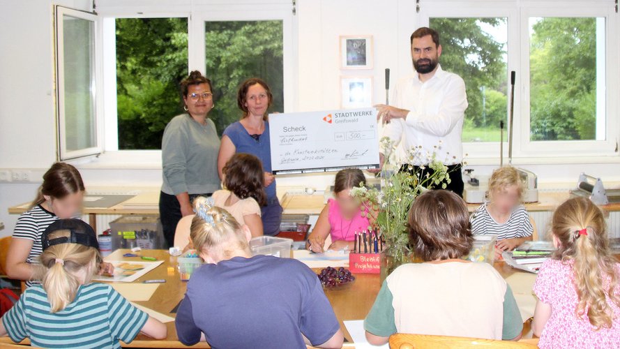 Foto (v.r.n.l.): Robert Kauert (Bereichsleiter Erzeugung/Wassergewinnung) übereicht einen symbolischen Spendescheck an die Kunstwerkstätten in Greifswald, vertreten von Isabelle Hoffmann (Mitarbeiterin Finanzbuchhaltung) und Martha Bahls (Leiterin Töpferkurs) 